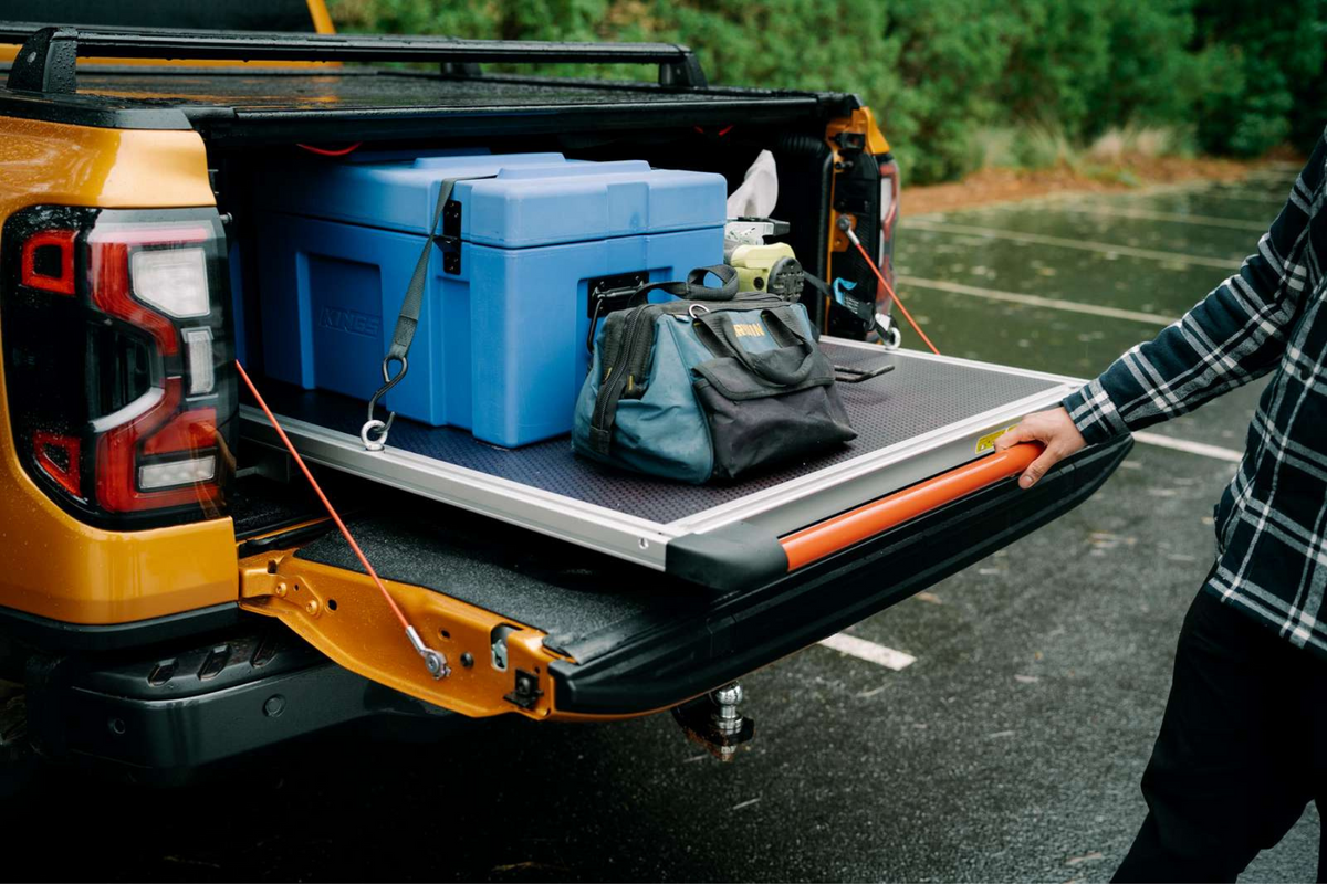 Loaded ute tray with camping gear and tools secured for transport.